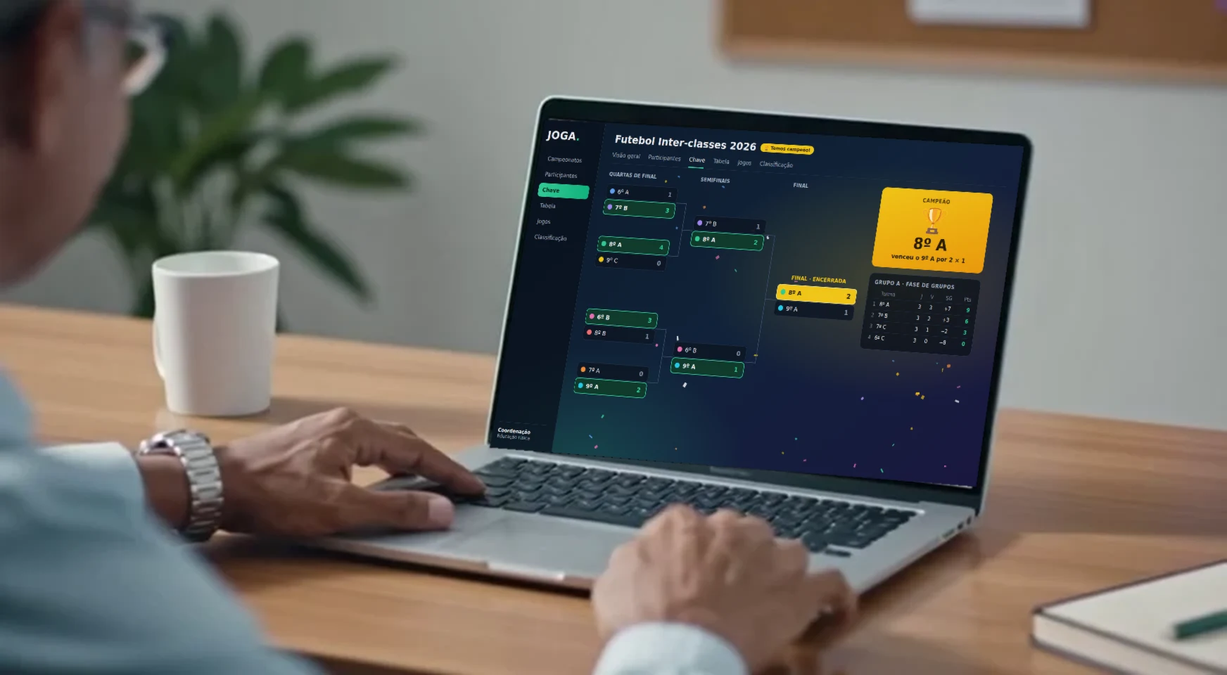 Um organizador usa o JOGA no notebook: a chave do Futebol Inter-classes, das quartas até a final, e a tabela do grupo ao lado.