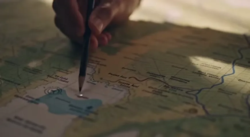 Operador debruçado sobre a mesa, detalhando um ponto do roteiro num mapa.