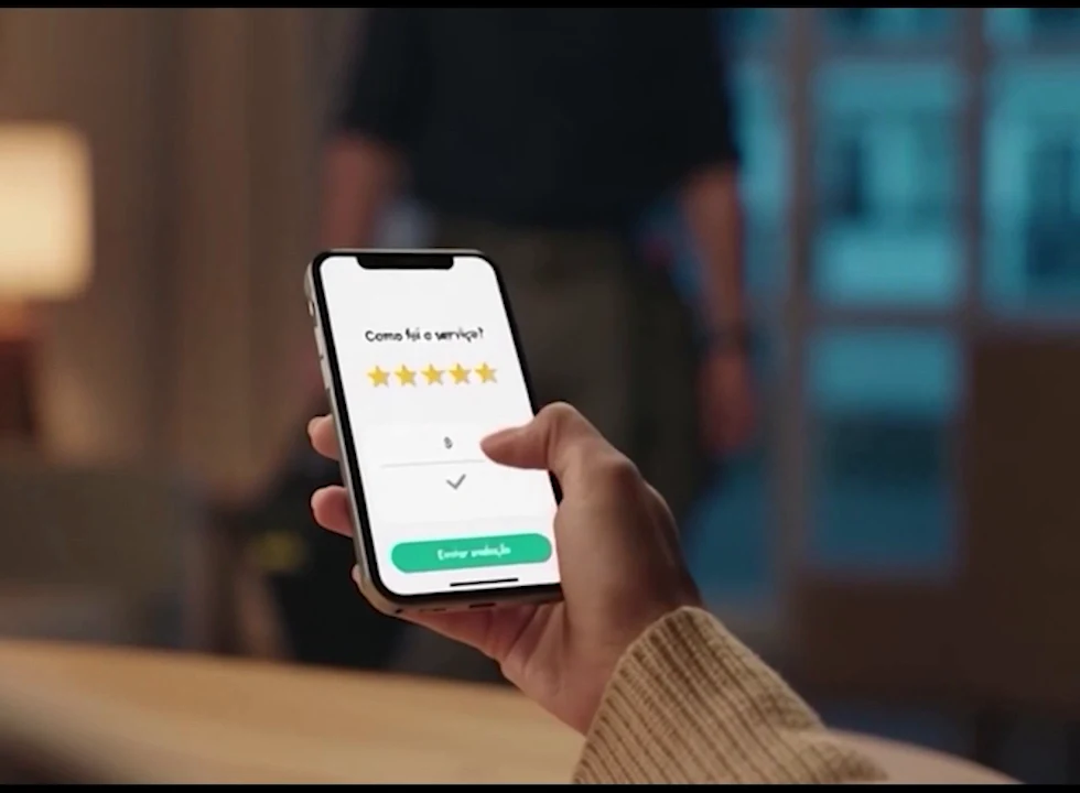 Mão segurando um celular com a pergunta 'Como foi o serviço?' e cinco estrelas selecionadas.